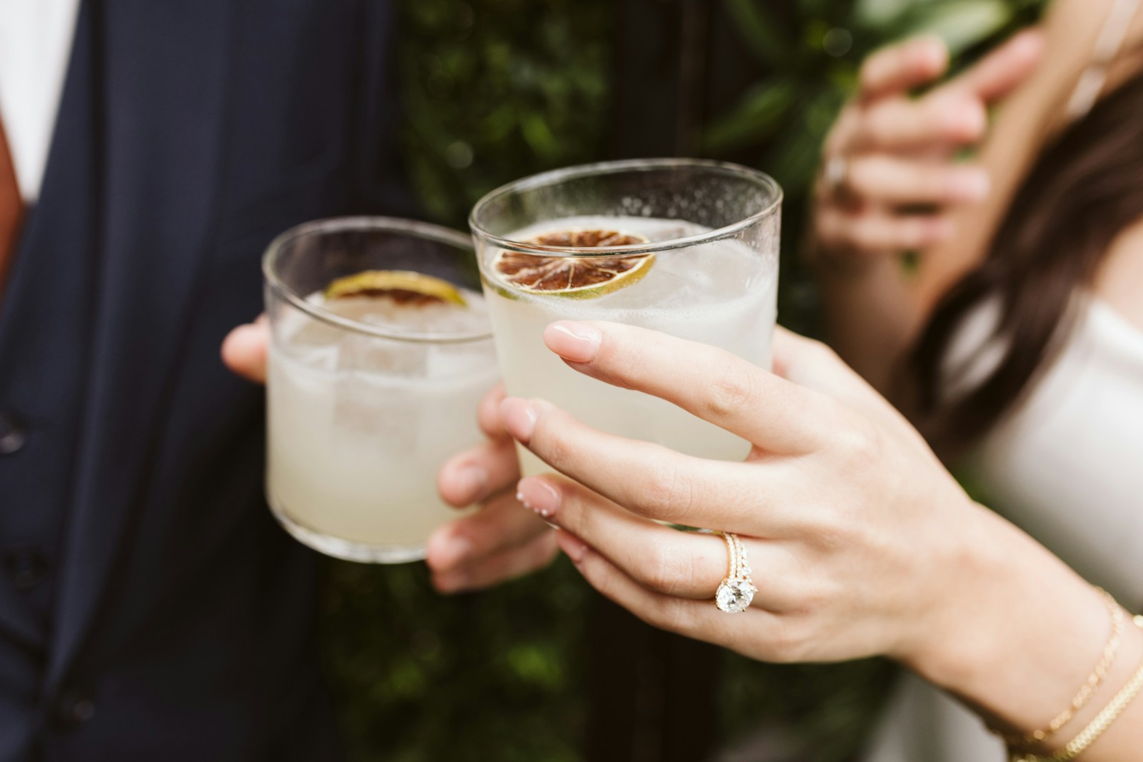 Zwei Cocktailgläser stoßen an, an ihrer Hand ein Verlobungsring
