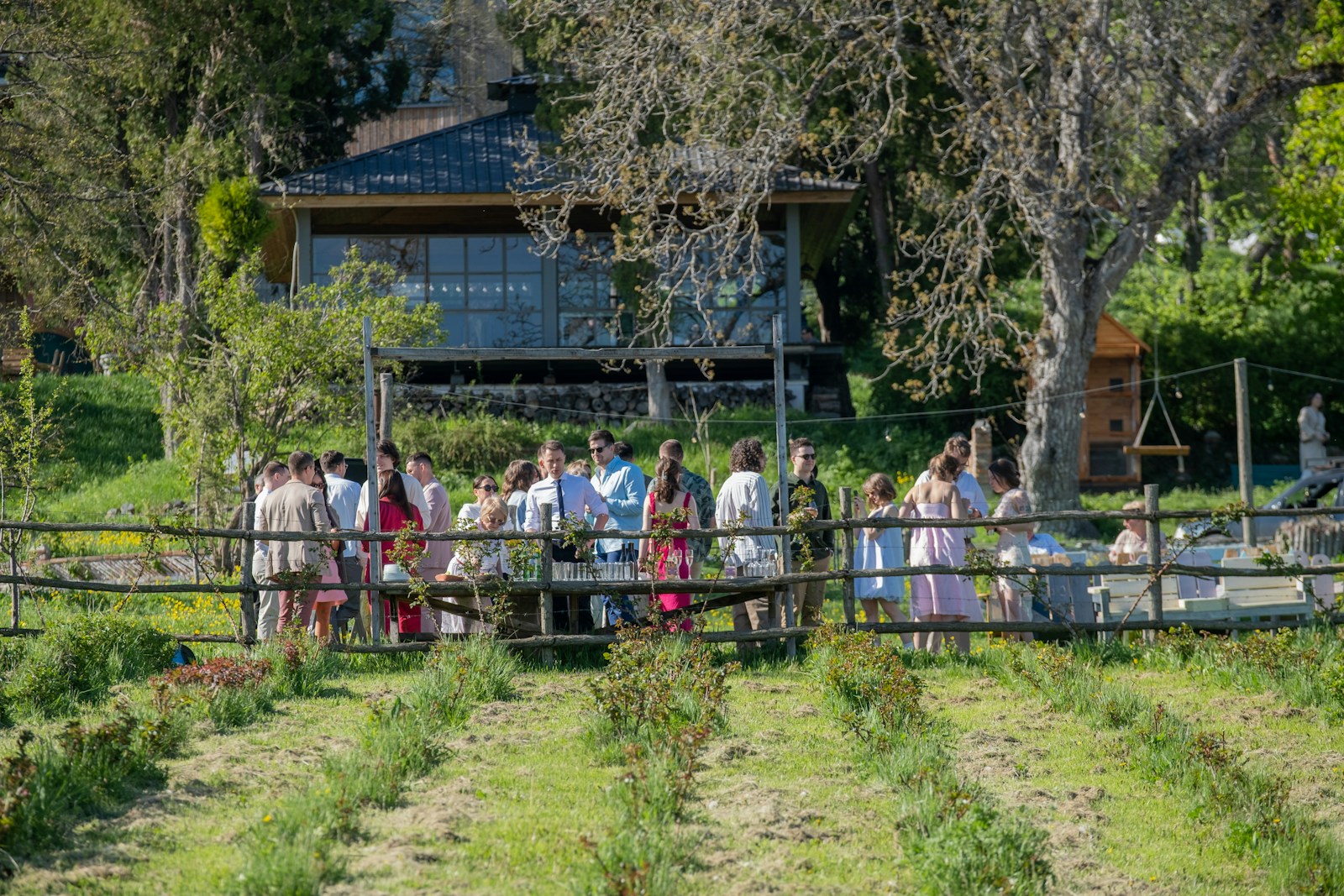 Hochzeitsgäste versammeln sich zum Empfang in einem sonnigen Garten auf dem Land