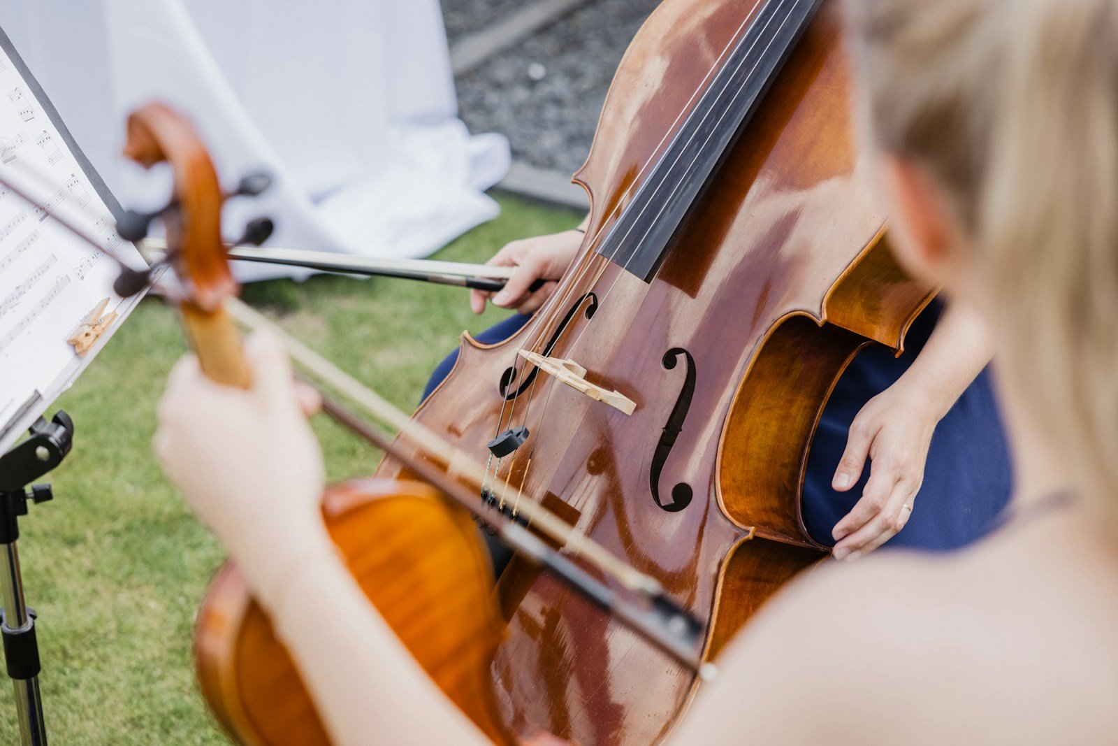Un duo de violon et violoncelle joue sur une pelouse, partition sur le pupitre